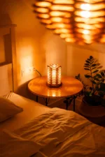 Stolni dřevěná lampa Tria Costa v interiéru potmě s lustrem.