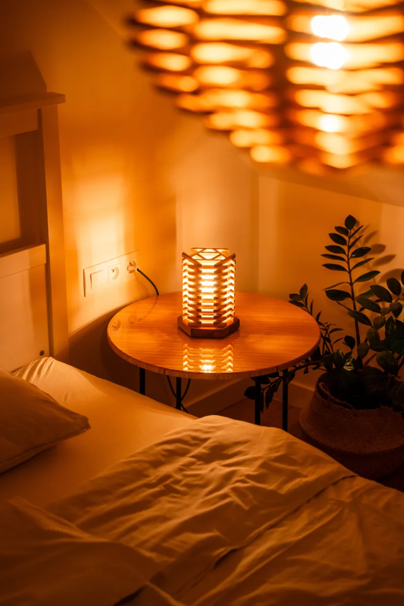 Stolni dřevěná lampa Tria Costa v interiéru potmě s lustrem.