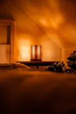 Stolni dřevěná lampa Tria Costa v interiéru potmě se stíny.