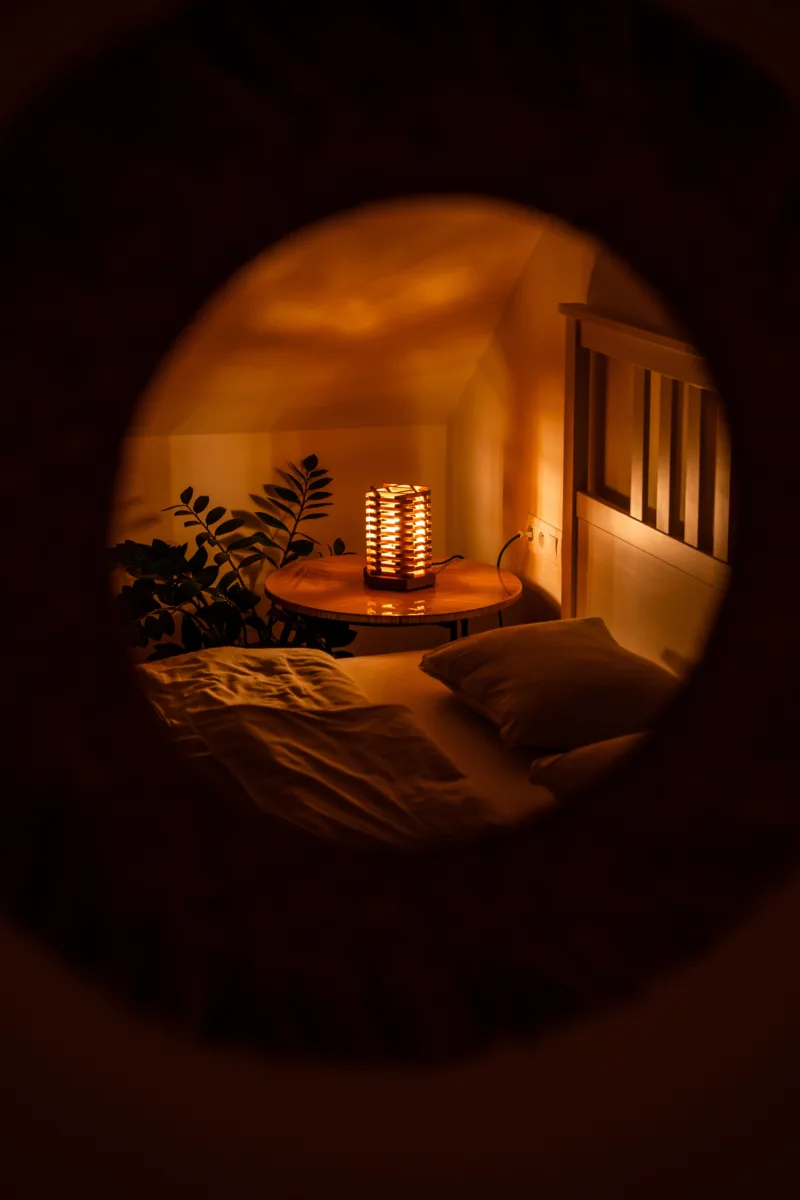 Stolni dřevěná lampa Tria Costa v interiéru potmě v zrcadle.