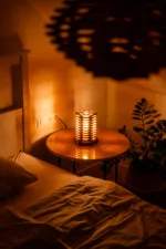 Stolni dřevěná lampa Tria Costa v interiéru potmě z nadhledu.