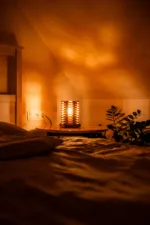 Stolni dřevěná lampa Tria Costa v interiéru potmě zboku.