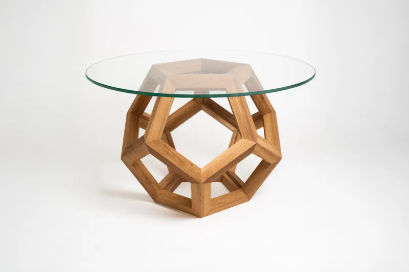 Elegantní konferenční stůl Bon Lioro s podnoží z dubových hranolů ve tvaru dodekaedru a tvrzenou skleněnou deskou Glase Cir o průměru 80 cm.