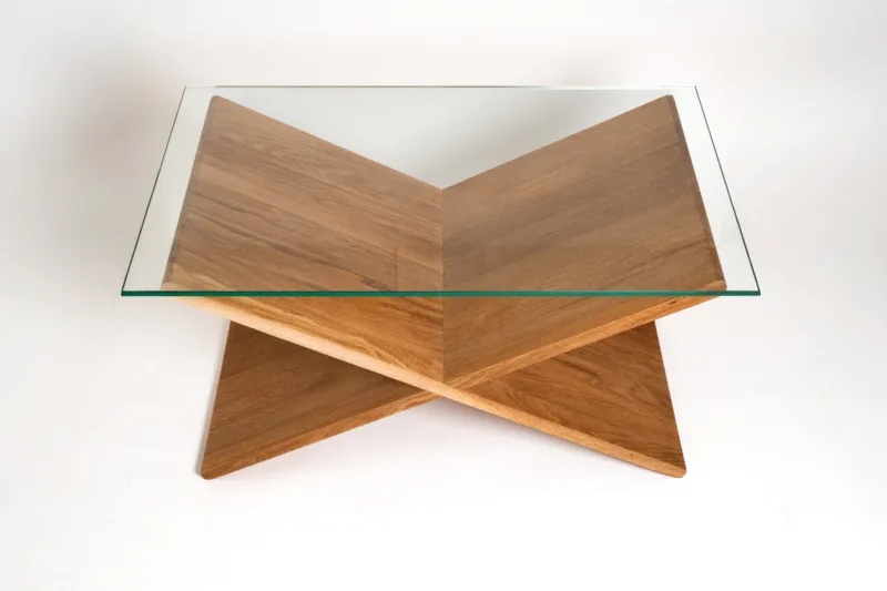 Designový konferenční stůl Bon Feris vyniká minimalistickým X-tvarem podnože z výběrového dubu. Kombinace dřeva s deskou o rozměru 90×55 cm působí vzdušně, ale zároveň stabilně. Pod skleněnou deskou vzniká praktický úložný prostor.