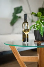 Konferenční dubový stůl Bon Veyra se skleněnou deskou Glase Cir 80 cm v interiéru pohled na detail láhve s vínem.