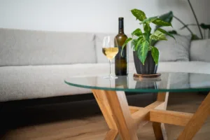 Konferenční stůl z masivního dubu Bon Veyra se skleněnou deskou Glase Cir 80 cm v interiéru detail láhev a víno.