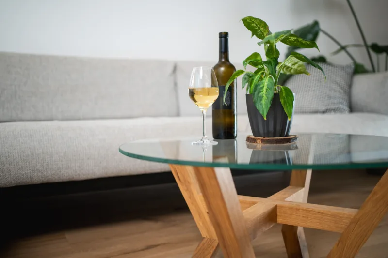 Konferenční stůl z masivního dubu Bon Veyra se skleněnou deskou Glase Cir 80 cm v interiéru detail láhev a víno.