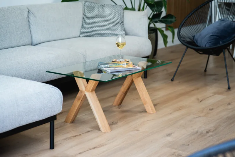 Konferenční stůl z dubového dřeva Bon Ravera se skleněnou deskou Glase Cirte v interiéru pohled z boku s vínem.