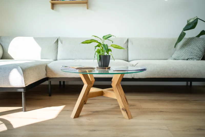 Konferenční dubový stůl Bon Veyron se skleněnou deskou Glase Cir 80 cm v interiéru pohled zepředu s rostlinou.